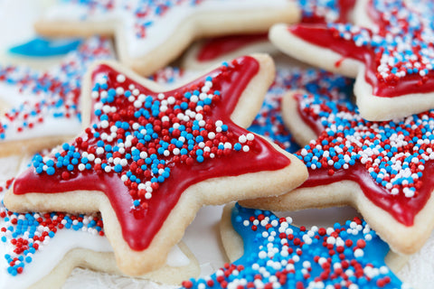 Star shaped cookies feature red and blue frosting as well as red, white and blue round sprinkles generously applied.