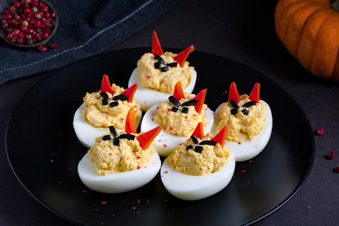 Deviled Eggs dressed with red pepper horns and angry olive eyes to resemble the devil.