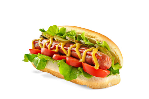 Grilled hotdog inside of a bun on a white background features lettuce, tomato and mustard drizzled across the top.