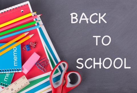 Notebooks, pencils and other school supplies on grey background with white text Back to School