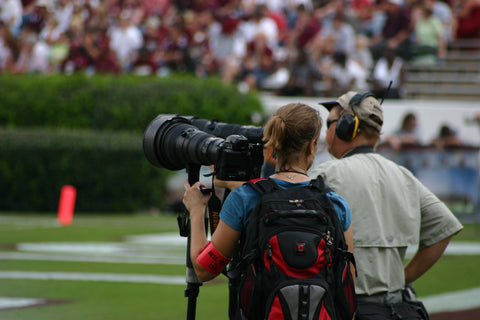 female photographer with a big lens on the sidelines