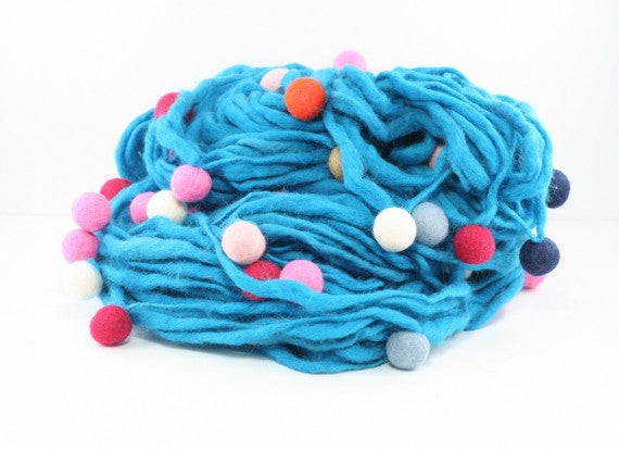 Hank of light blue thick and thin yarn with felt balls on white background