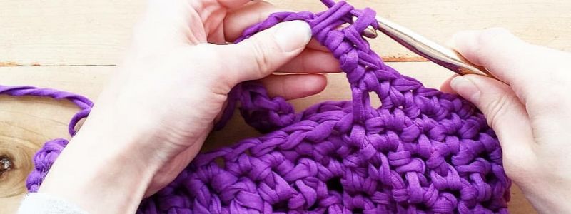 Someone crocheting a purple market tote