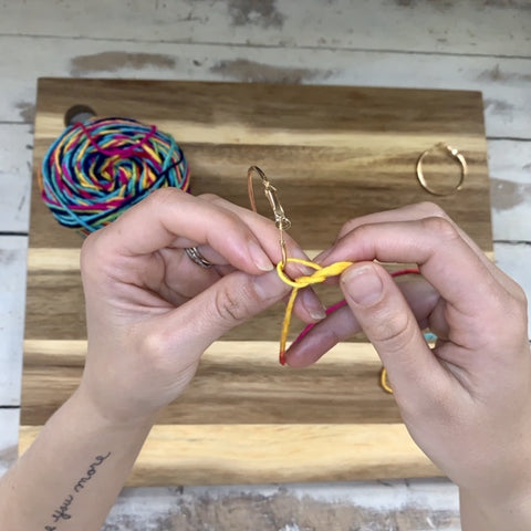 Hands making a half knot on the earring hoop