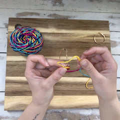 Hands making spiral knots on earring loops