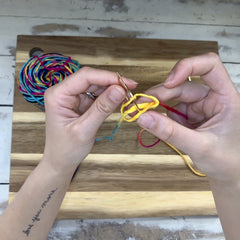 Hands making spiral loops on golden earring hoops