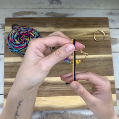 Hands binding off yarn on gold earring hoops