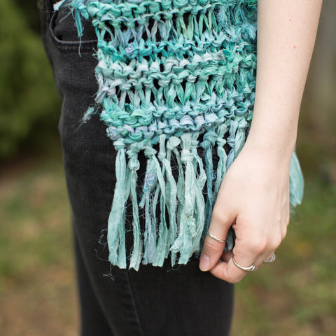 Close up of woman wearing black jeans and turquoise Silk Hippie Fringe Vest