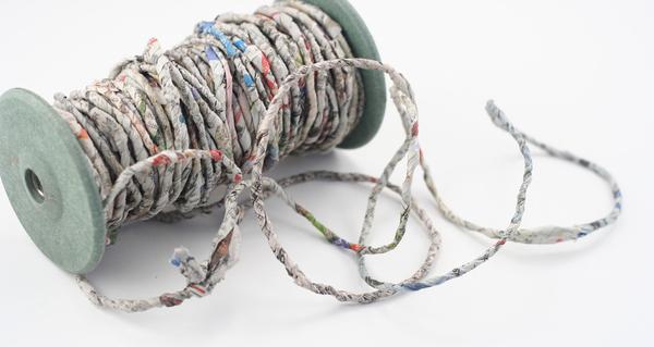Large spool of newspaper yarn sitting on a white background