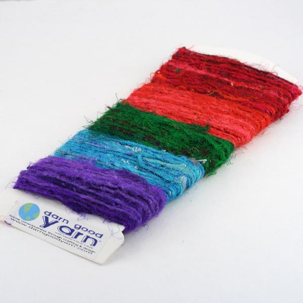 White sample card full of yarn samples in purple, blue, green, orange, and red all on a white background