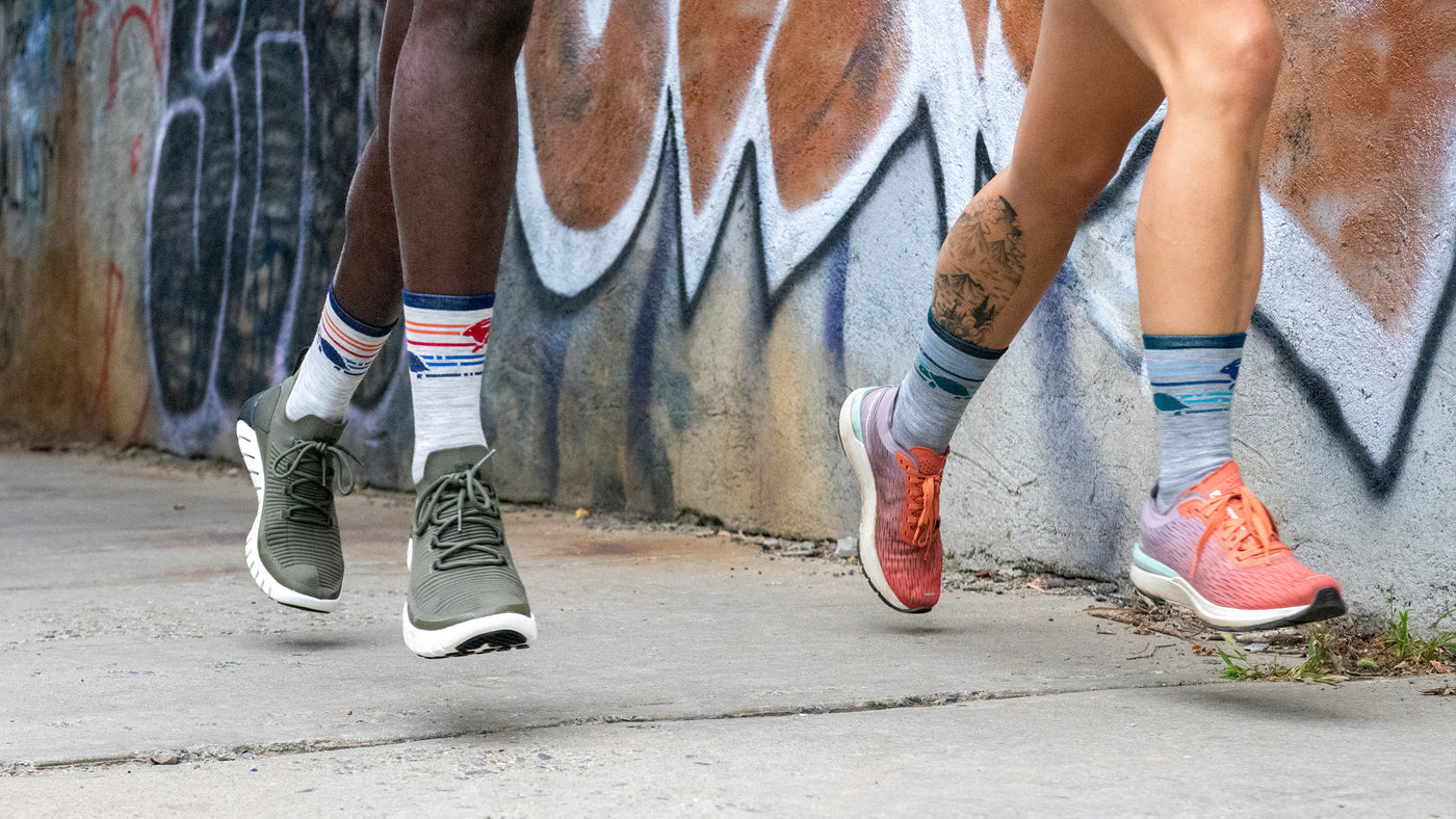 Runner wearing red trainers and white ankle running socks from darn tough