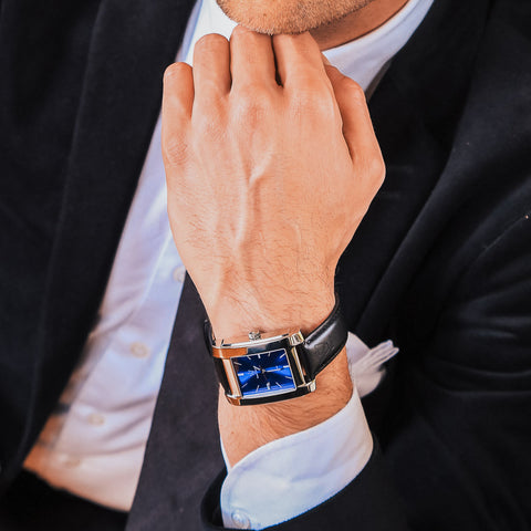 Herrklocka i polerat stål med blå klassisk urtavla - närbild på klocka och arm man poserar