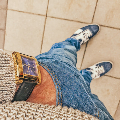 Herrklocka i polerat guld med blå klassisk urtavla - klockan ses uppifrån med handen i vänster ficka