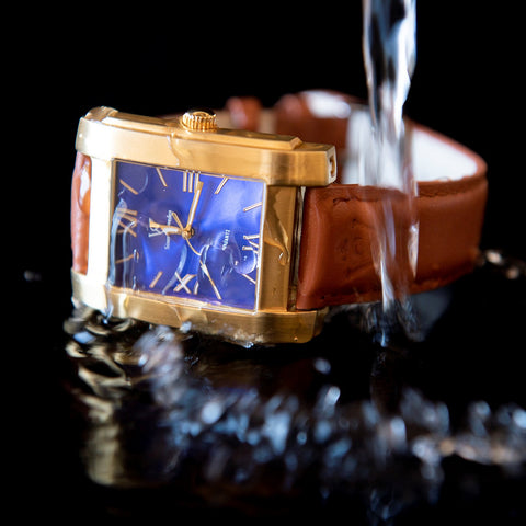Fyrkantig herrklocka i borstat guld med blå urtavla - vatten hälls på klocka