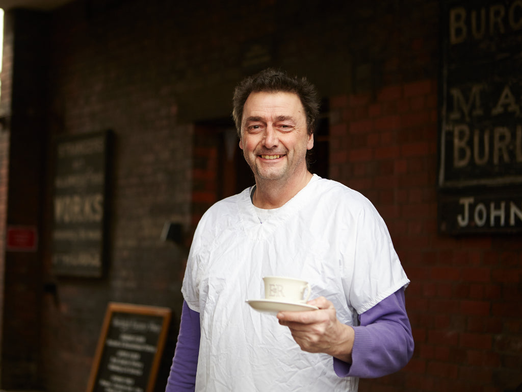 Pottery worker holding a teacup and saucer made by Burleigh Pottery