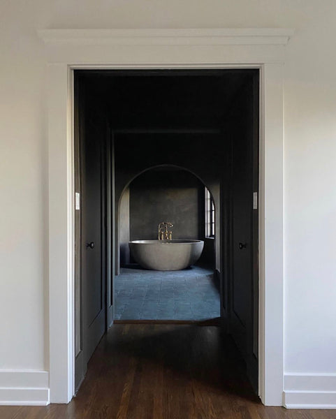A white room, leading through a dark corridor to a beautiful modern bathtub - designed by Jake Alexander Arnold