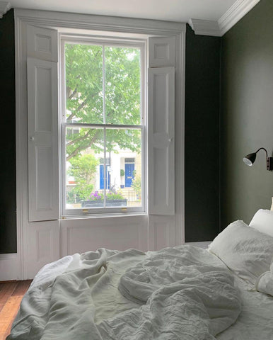 a bedroom with an unmade bed and dark green walls
