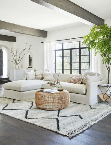 a large moroccan shag rug styled with a large white linen sofa and a wicker pouf