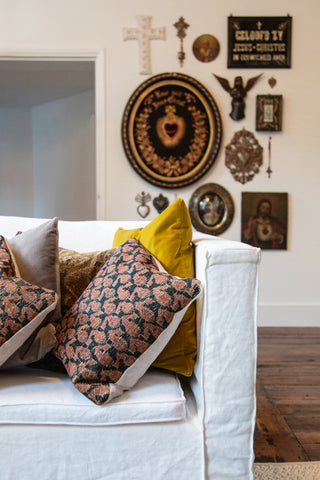 a white linen sofa with various scatter cushions propped in the corner. An antique mural is visible in the background