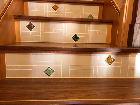 stair risers tiled with plain handmade tiles made by heath ceramics and feature tiles depicting multi-colored aspen leaves made by emu tile