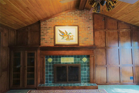 wood paneled library with green art tile fireplace surround