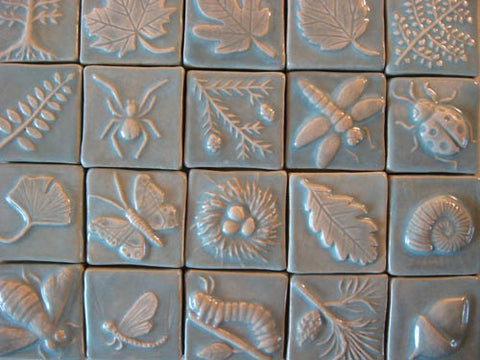 small handmade tiles depicting plants and animals