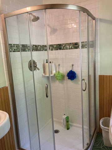 tiled shower with white subway tiles and a green stripe of glass and handmade feature tiles