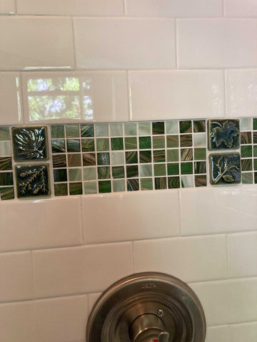 tiled shower with white subway tiles and a green stripe of glass and handmade feature tiles