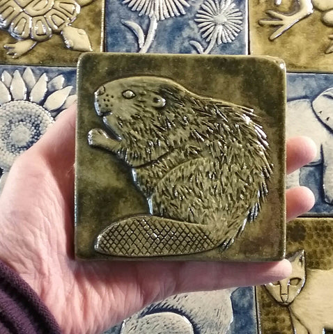 beaver handmade tile, four inch size, held in hand above other tiles
