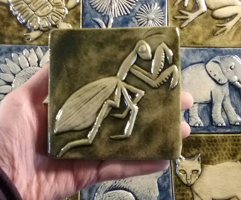 mantis handmade tile in hand over other tiles, 4"x4" size, copper green glaze