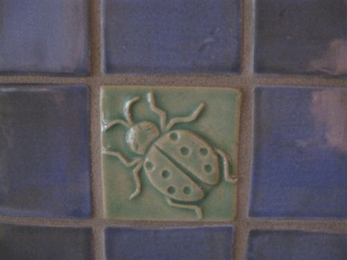ladybug art tile installed with handmade field tiles
