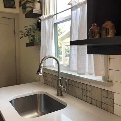 periwinkle handmade tiles featuring plants and animals installed in a kitchen sink backsplash