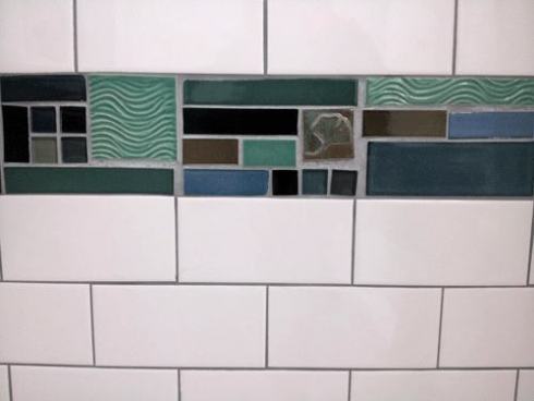 blue and green glass mosiac and white subway tile shower with art tile details