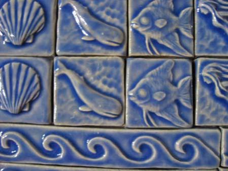 close up of blue art tiles depicitng sea creatures and waves