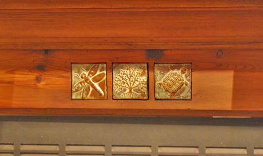 art tiles in a wooden fireplace surrpuound- dragonflu, tree, turtle