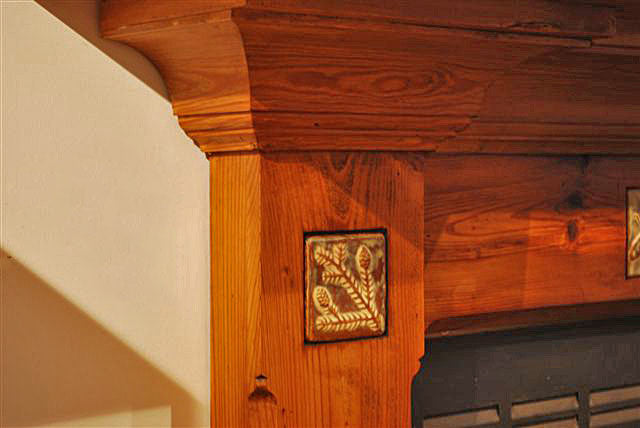 Close up of Hemlock Art Tile inlayed in wood fireplace surround