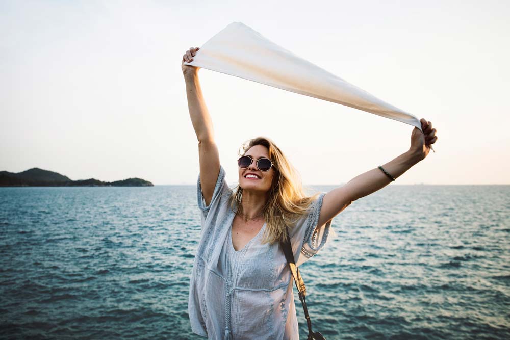 Happy woman raises arms by the sea