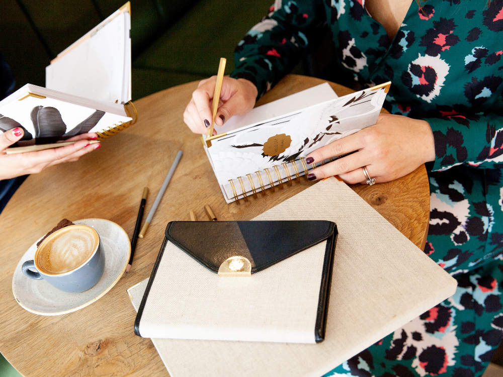 woman sat at table writing in a planner