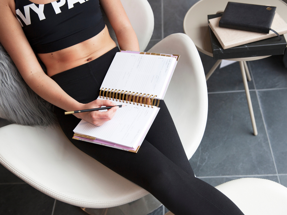 woman in gym kit relaxing with a day planner diary