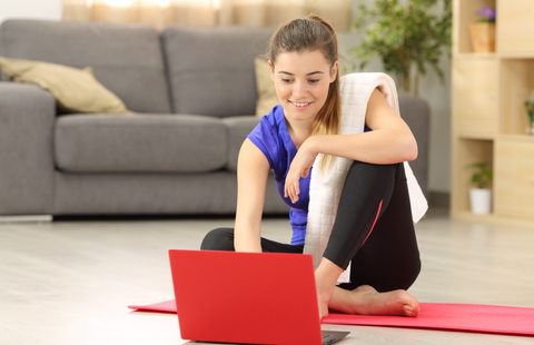 woman selecting tutorial before exercise sitting on the floor in the living room at home