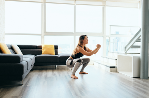 woman squatting in living room working out from home