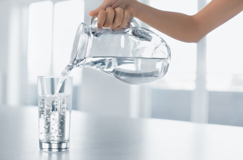 Woman's Hand Pouring Fresh Pure Water From Pitcher Into A Glass