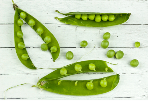 peas in pods on wooden surface