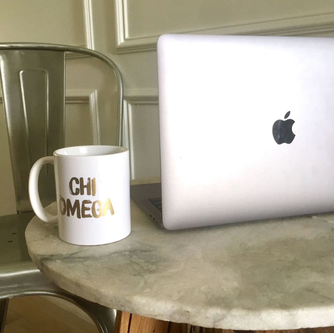 Sorority greek lettered mug next to laptop on table