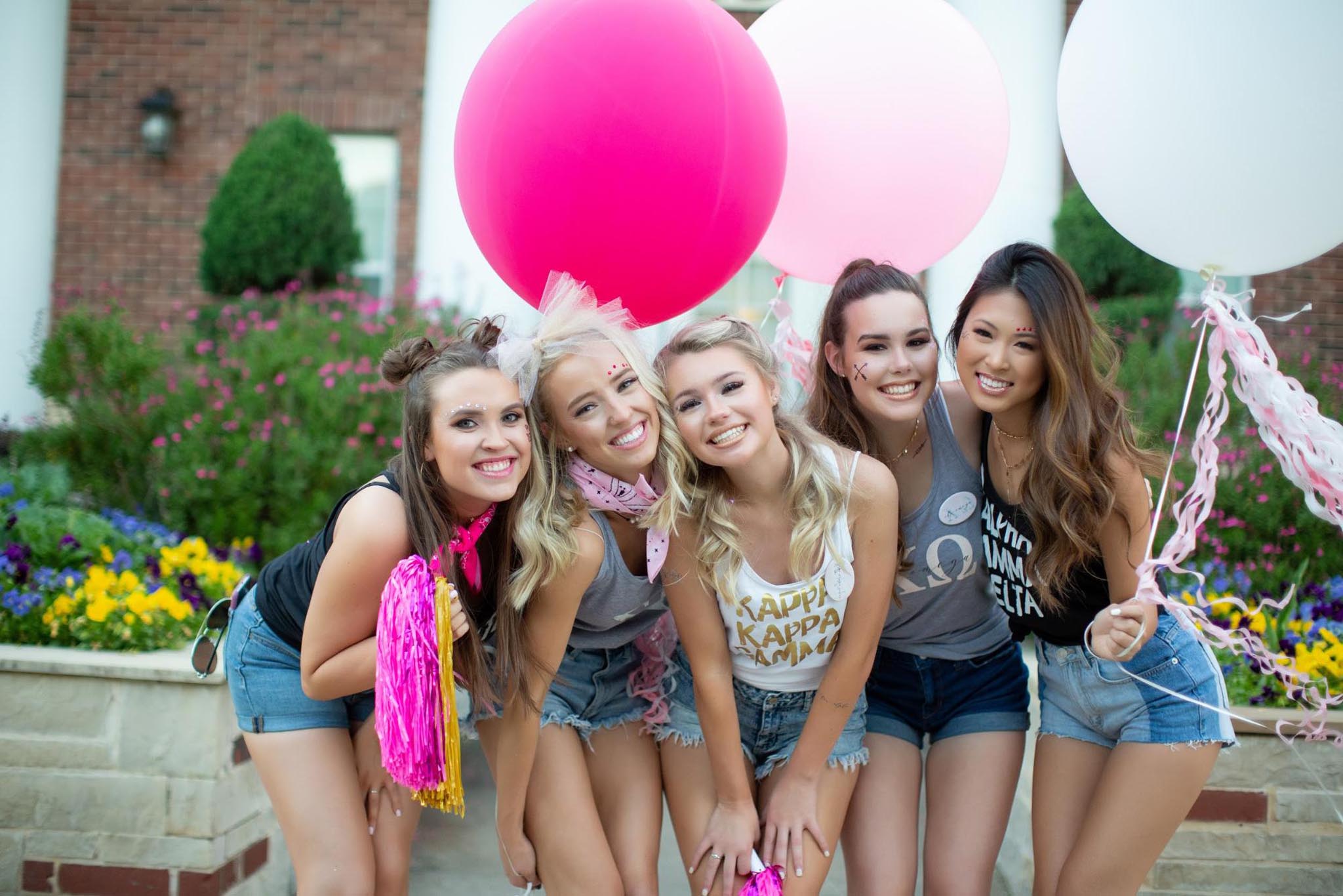 Sorority girls posing together holding large colorful balloons