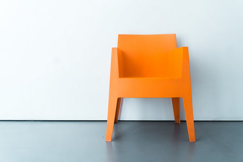 Bright orange chair infront of a white wall