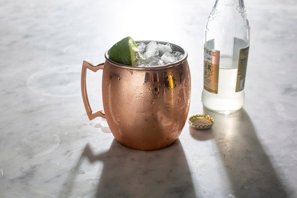 copper mug filled with liquid ice and lime beside a bottle