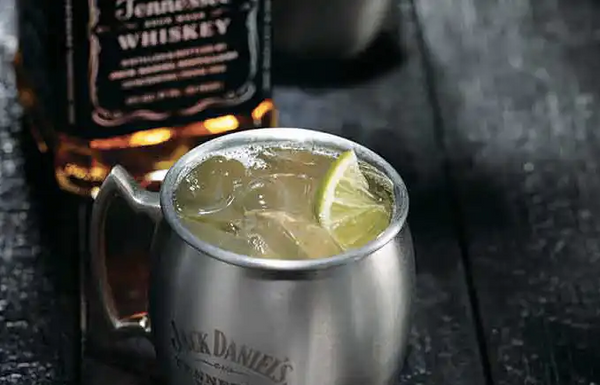 silver Jack Daniels mug filled with liquid ice and sliced lime 