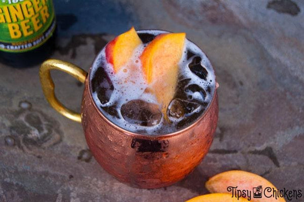 copper mug filled with liquid peach slices ice cubes top view
