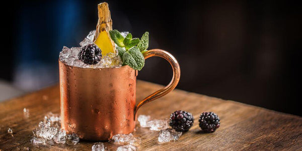 copper mug filled with ice blackberry and mint leaves